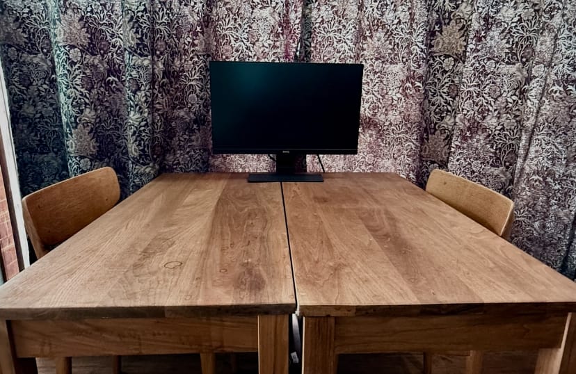 写真:ストレンジブレイン株式会社ミーティングルーム。木製のデスクに木製の椅子が2脚用意されている。
